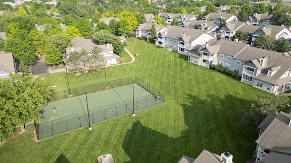 A tennis court is surrounded by houses and trees at Sandstone Creek, Overland Park, 66223.