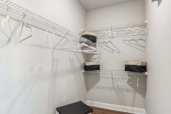 A white closet with clothes hanging on hangers.