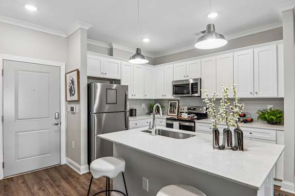 A kitchen with white cabinets and a white island.