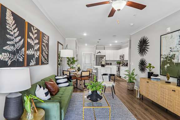 A living room with a green couch and a fan on the ceiling.