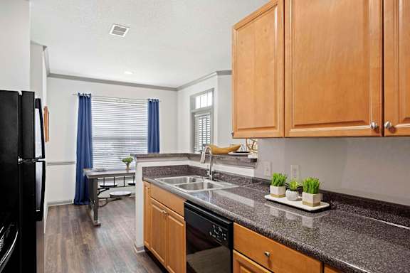 A kitchen with wooden cabinets and a black refrigerator at The Shallowford Apartments, Chattanooga, TN 37421