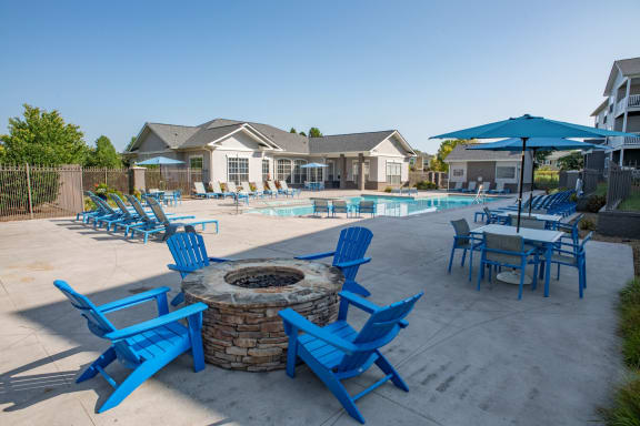 our apartments have a pool and patio with blue chairs and umbrellas at The Shallowford, Chattanooga, TN, 37421