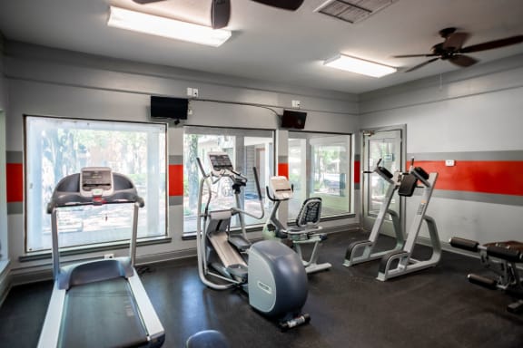 a gym with various exercise equipment and windows at The Summit Apartments, Memphis