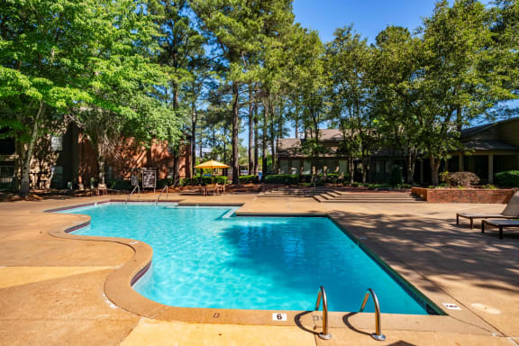 a swimming pool with trees and a building in the background at The Summit Apartments, Tennessee