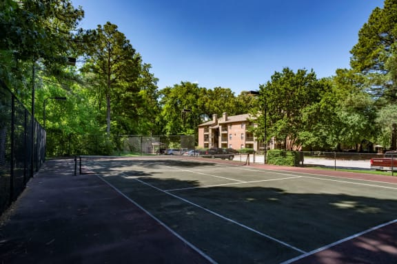 a tennis court with a building in the background at The Summit Apartments, Memphis