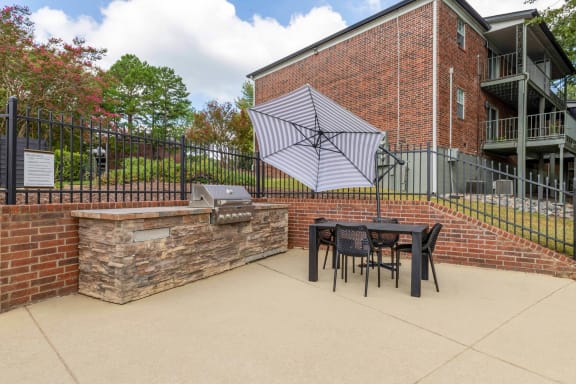 our patio has a grill and a table with chairs and an umbrella at The Waters at Chenal, Little Rock