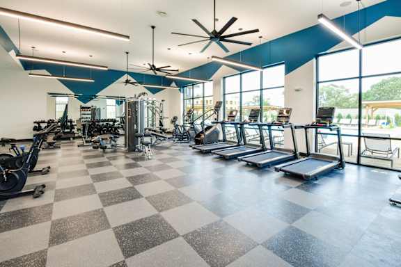 A gym with a variety of equipment including treadmills, weights, and exercise machines.