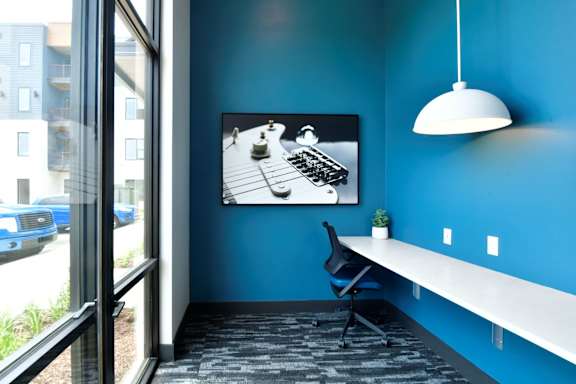 A blue room with a white desk and a black chair.