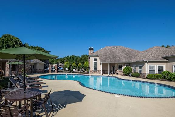 A large swimming pool surrounded by chairs and umbrellas.