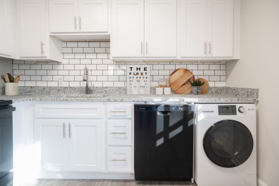 a white kitchen with white cabinets and a washing machine