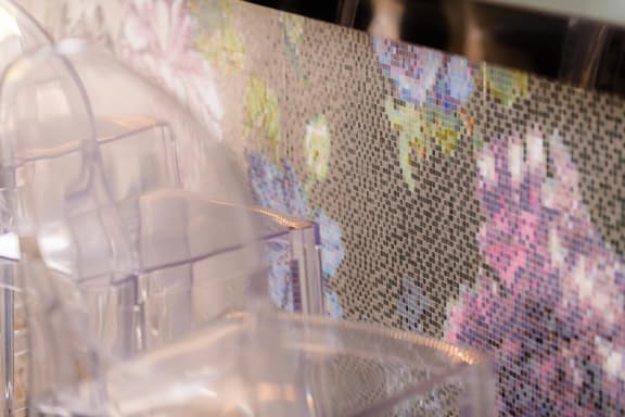 a person standing in front of a mosaic wall with a chair at The Villa at River Pointe, Maumelle, Arkansas