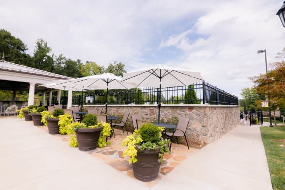 a patio with chairs and umbrellas and a stone wall at The Villa at River Pointe, Arkansas, 72213
