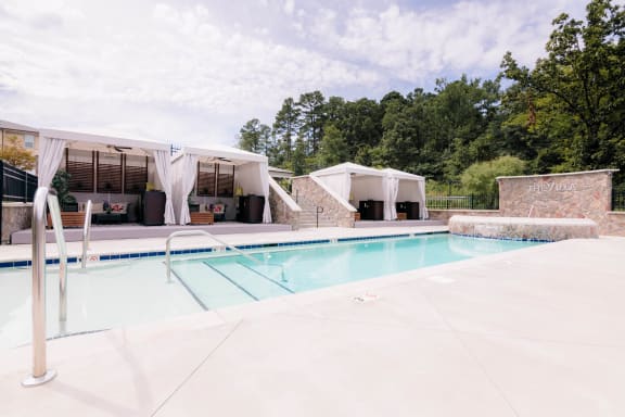 a swimming pool in front of a pool house with tents at The Villa at River Pointe, Arkansas, 72213