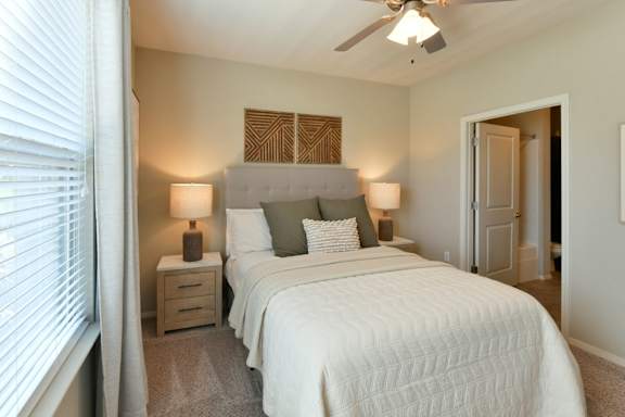 A bedroom with a large bed and a ceiling fan. at Hall Creek Apartment Homes, Arlington, TN