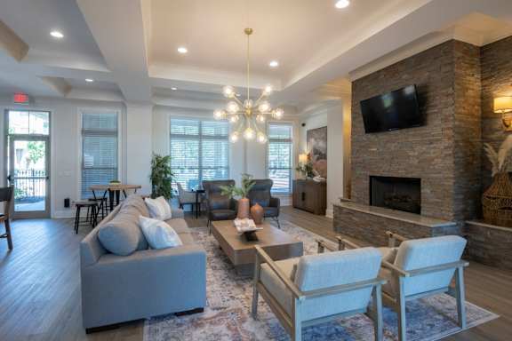 A living room with a grey couch, a fireplace, and a chandelier. at Hall Creek Apartment Homes, Arlington, Tennessee