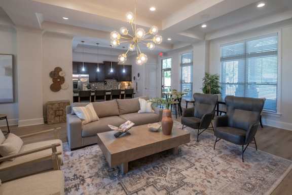 A living room with a large couch, a coffee table, and a chandelier.