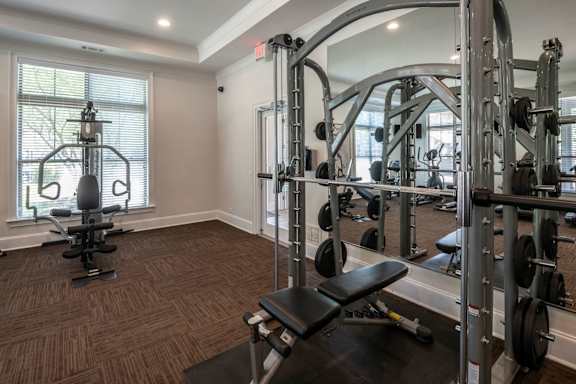 A gym with a squat rack, bench, and weights. at Hall Creek Apartment Homes, Arlington
