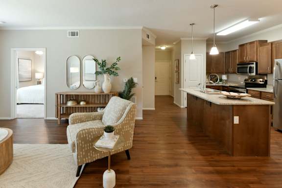 A well-lit kitchen with wooden floors and a dining area with a chair and table.