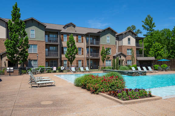 A large apartment complex with a pool and lounge chairs. at Hall Creek Apartment Homes, Arlington 38002