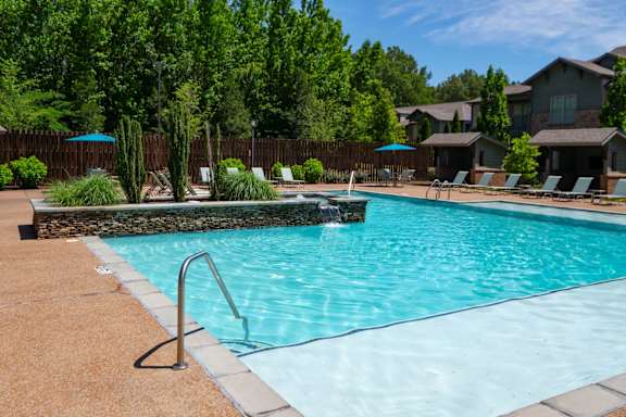 A swimming pool surrounded by trees and a fence. at Hall Creek Apartment Homes, Arlington, TN
