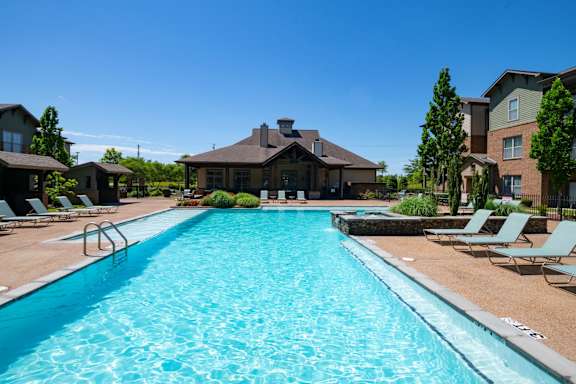 A large swimming pool in front of a house with a brown roof.