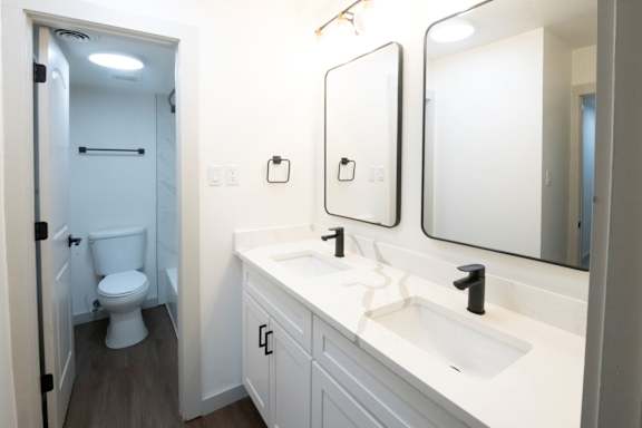 A white bathroom with a toilet, sink, and mirror.