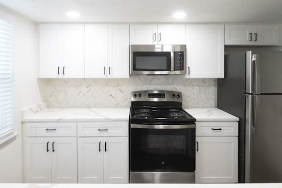 A kitchen with white cabinets and a black stove top oven.