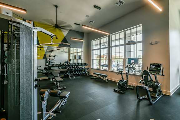 A gym with a variety of equipment including weights and cardio machines. at Grays Creek Apartments, Cordova