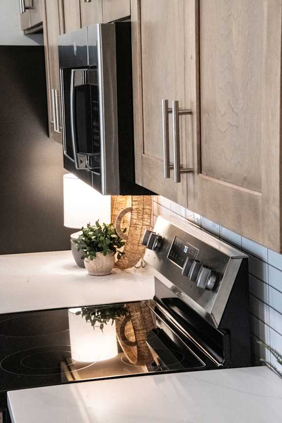 A modern kitchen with a stove top oven and a microwave above it. at Grays Creek Apartments, Cordova