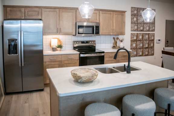A kitchen with a refrigerator, microwave, oven, sink, and bar stools. at Grays Creek Apartments, Cordova, TN, 38018