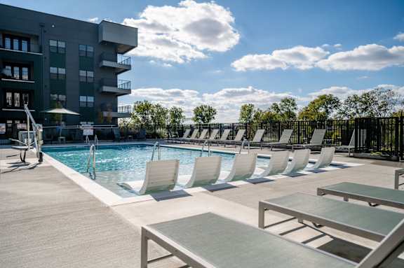 A pool area with sun loungers and a building in the background at Harbor Side at Conwood Flats Apartments, Memphis