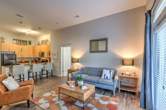 A living room with a grey couch, a brown armchair, and a coffee table at Highland Row Apartments, Memphis