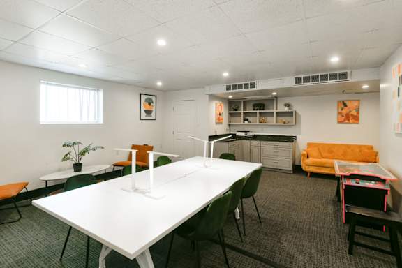 A conference room with a white table and green chairs.