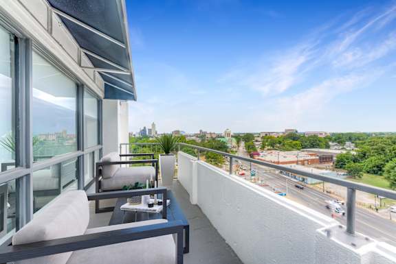 A balcony with a table and chairs overlooking a busy street.at Iris Luxury Apartments, Memphis, TN 38105
