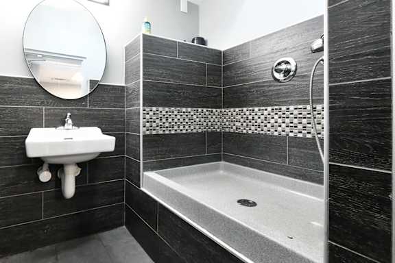 A bathroom with a sink, mirror, and shower.