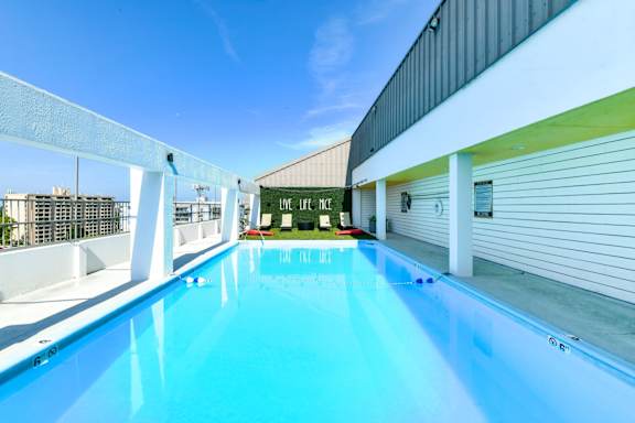 A swimming pool with a blue tinted water and a white fence around it.