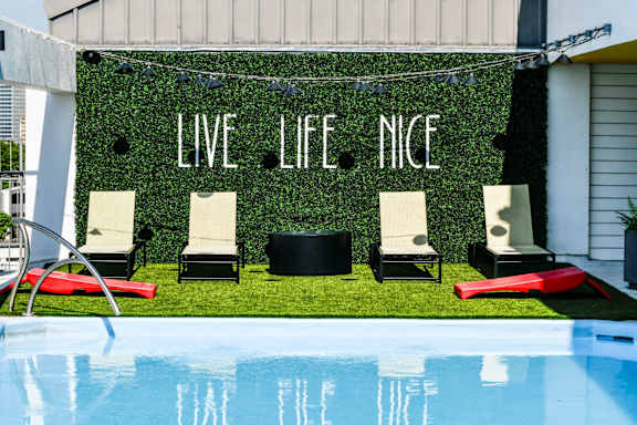 A pool with chairs and a sign that says "Live Life Nice".