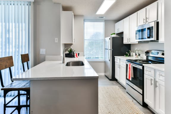 an open kitchen with white cabinets and black appliances and a white counter top
