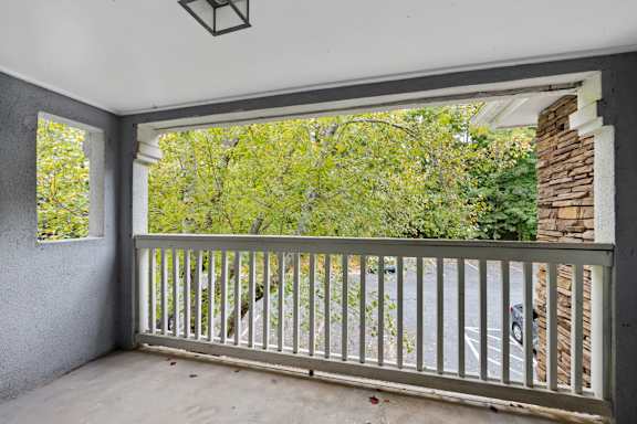 A balcony with a white railing and a view of trees and a parking lot. at Mill House at East Cobb, Georgia