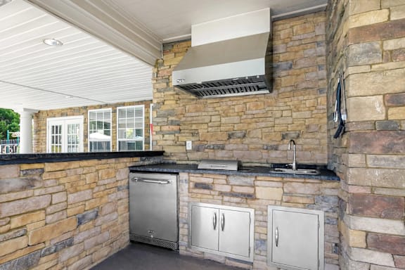 A kitchen with a stone wall and a stainless steel dishwasher.