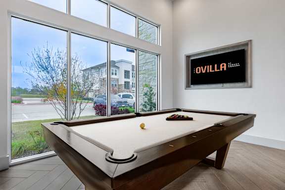 A pool table in a room with a picture of a building on the wall.
