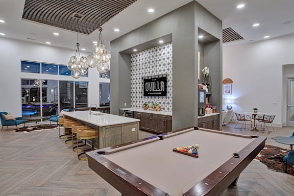 A pool table is in the middle of a room with a shiny wooden floor.