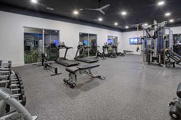 A spacious gym with a variety of equipment including treadmills, elliptical machines, and weight machines.