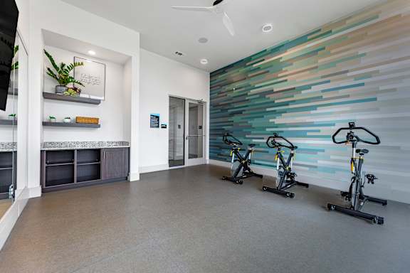 A room with exercise bikes and a wall of tiles.