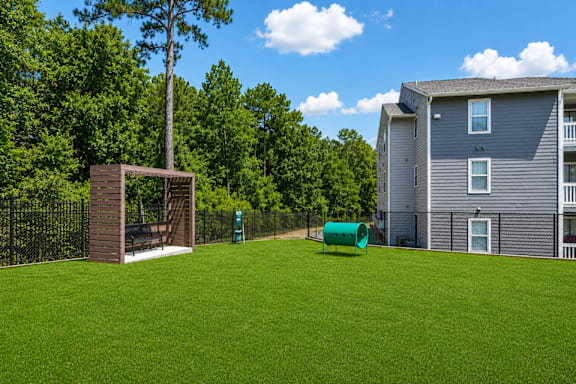 A green lawn in front of a grey building and a brown structure.