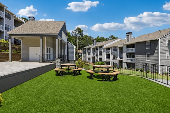 A sunny day at the apartment complex with picnic tables in the grassy courtyard.