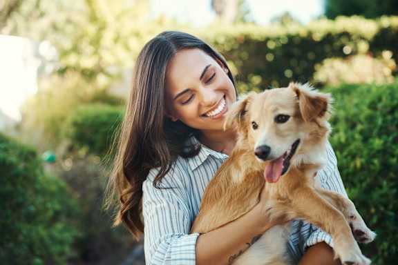 A woman is hugging a happy dog in a garden at Kiwi Goji Apartments, Memphis