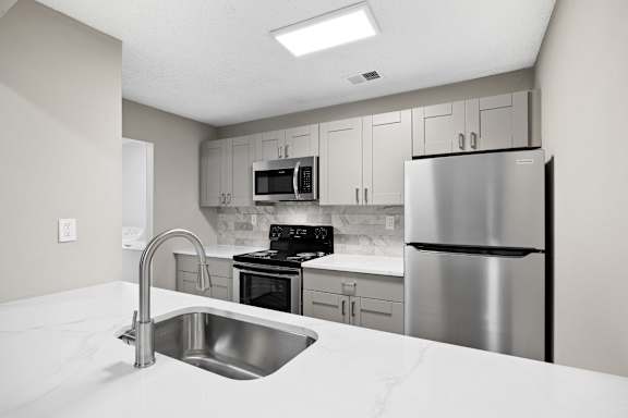 A kitchen with a stainless steel refrigerator, microwave, oven, and sink. at Station Heights, Georgia