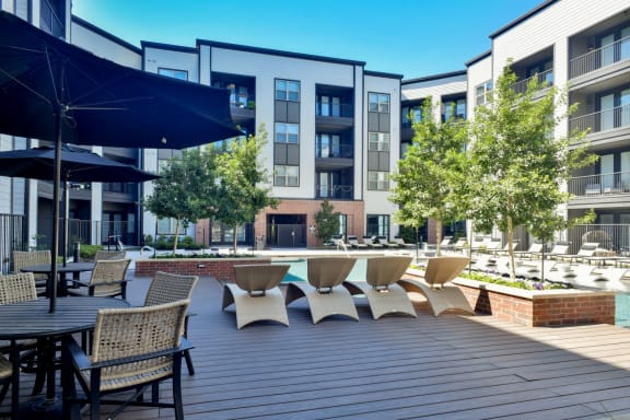 a large patio with tables and chairs and a swimming pool at Station at Old Town, Lewisville