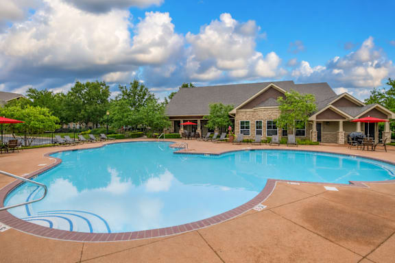 A large outdoor swimming pool with a small building behind it.